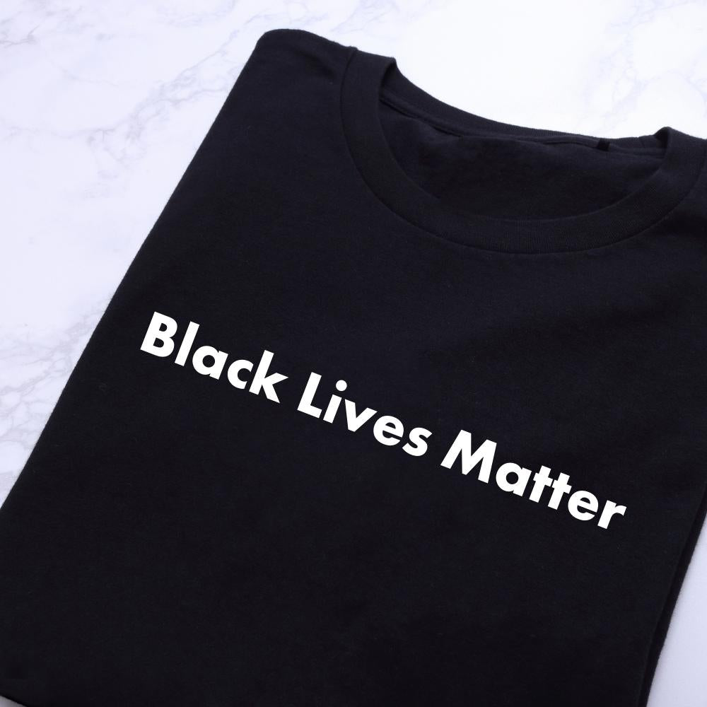 A black t-shirt is folder up on a marble floor or counter. It has a statement on it that says "Black lives matter" on it to support the BLM movement.