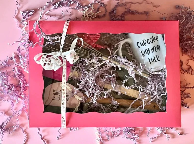 A gift box filled with cupcake baking essentials. The box is pink and is a cupcake box which measures 14 x 10 x 4 in.